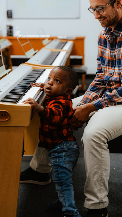 A prospective student plays the keyboard with his dad